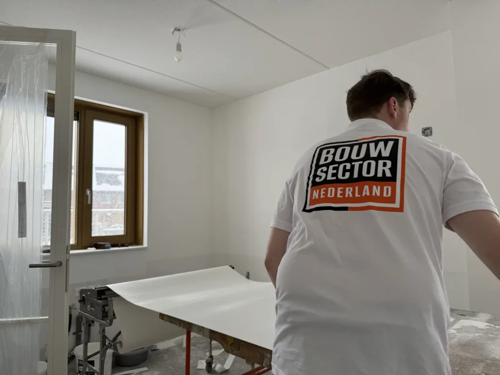 Behanger van Bouwsector Nederland met een baan vlies op de plaktafel in een afgedekte kamer
