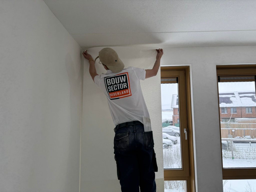Vakman van Bouwsector Nederland brengt een baan vlies aan tot tegen het plafond